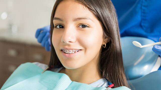 Adolescente con brackets sonriendo en consulta dental Adolescente con brackets sonriendo en consulta dental